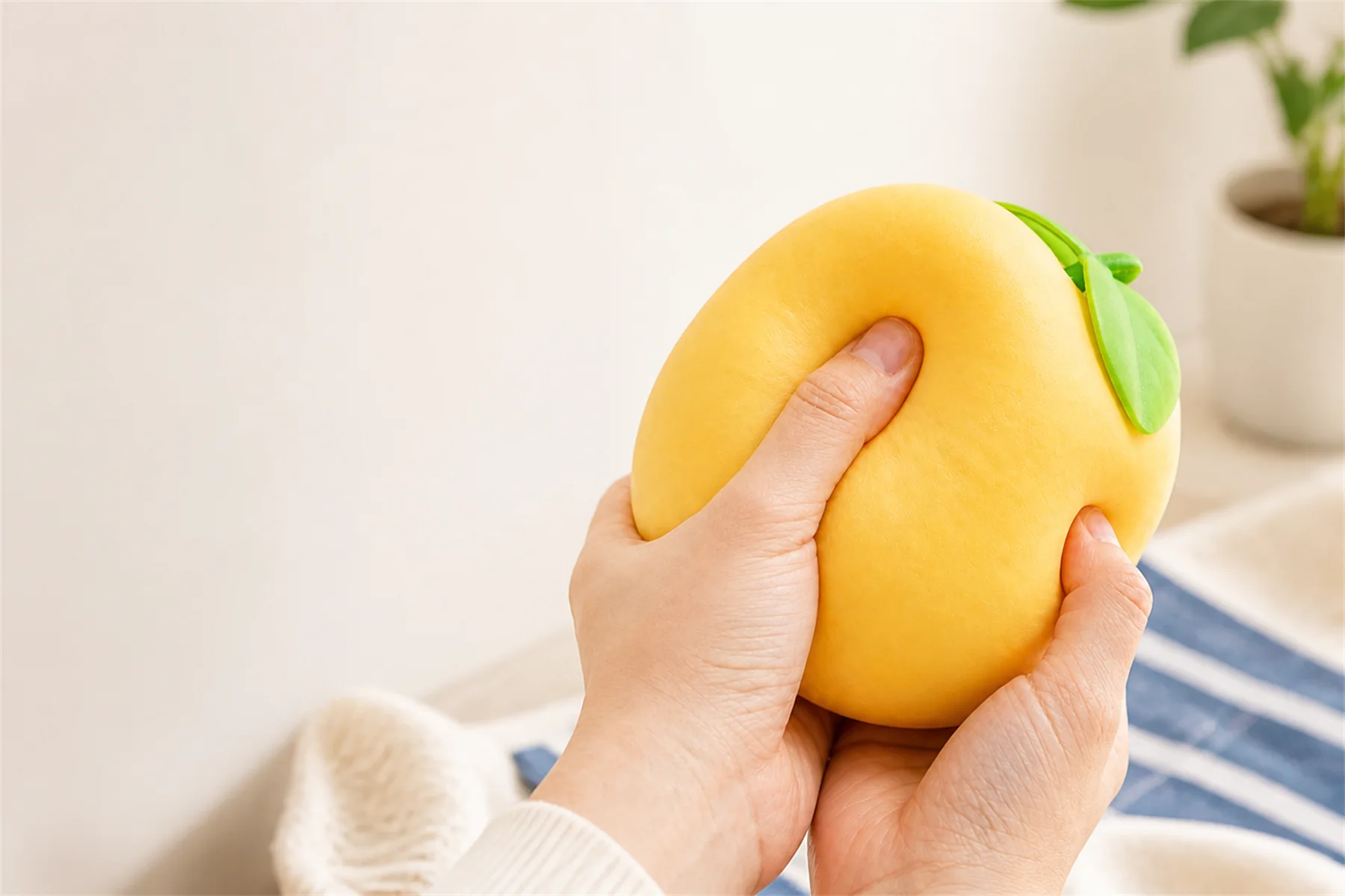 Hands compressing a large custom yellow fruit-shaped squishy